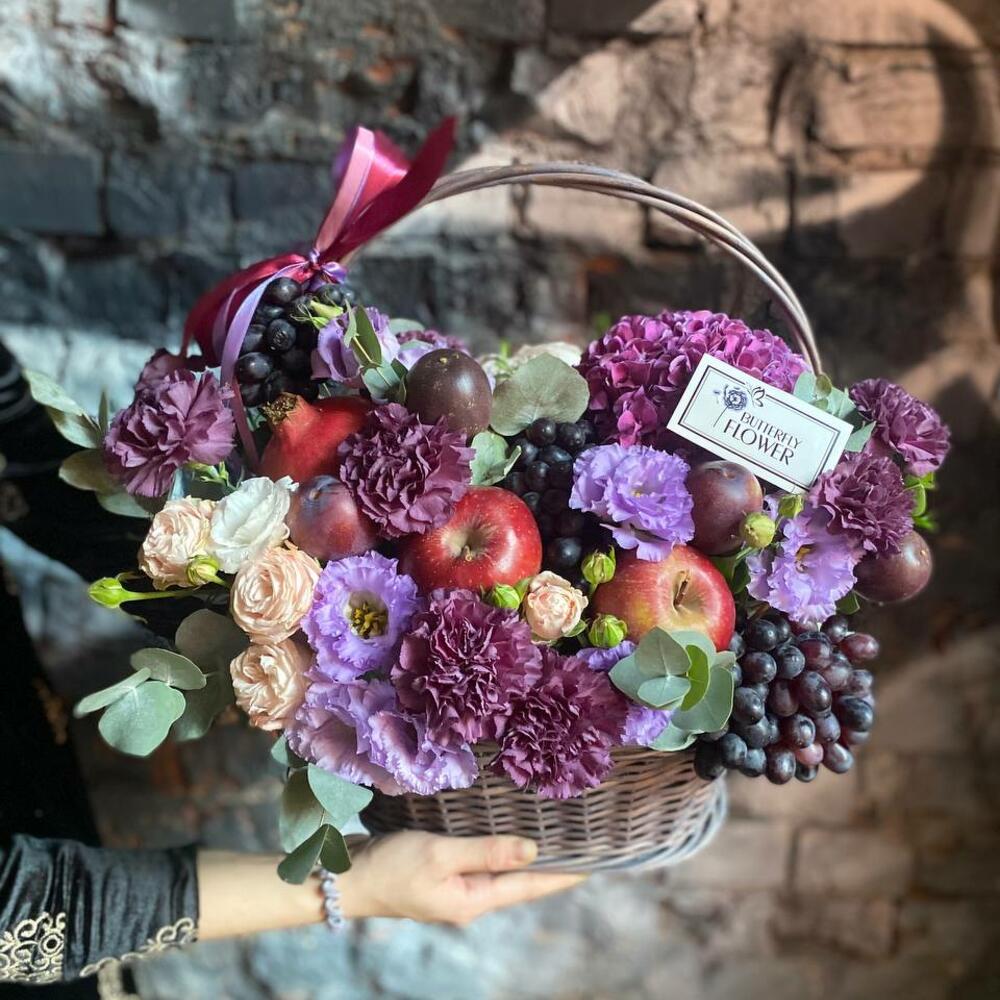 Съедобный букет из гортензии, диантусов, эустомы, кустовых роз, граната и винограда в плетеной корзине 